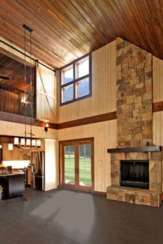 a large open living room with stone fireplace and wood paneled walls, high ceilings