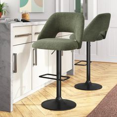 two green bar stools sitting on top of a wooden floor next to a counter