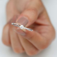 a woman's hand holding a ring with a diamond on it and the middle finger