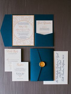 the wedding stationery is blue and gold with a wax seal on it's pocket