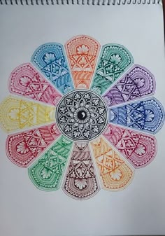 a drawing of a flower with many colors in the center, on top of a white paper