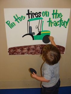 a young boy is painting a sign on the wall that says run the tires on the tractor