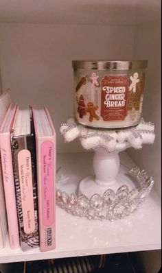 a candle and some books on a shelf in a room with white shelves filled with books