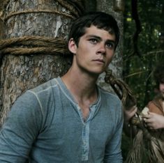 two young men standing next to each other in the woods, one is holding something