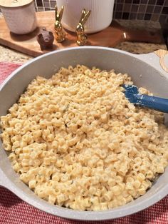 a bowl full of macaroni and cheese with a blue spatula in it