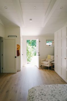 an open door leading to a bedroom with white walls and wood floors, along with a bed