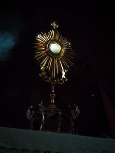 a large golden clock on top of a metal pole in the middle of a dark room