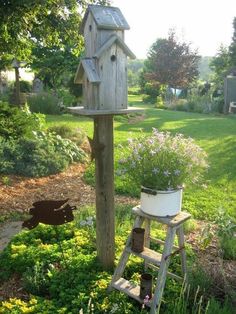 a wooden bird house sitting on top of a tree stump next to a planter