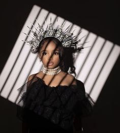 a woman with a crown on her head standing in front of a white and black wall