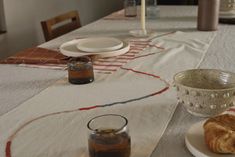 the table is set with croissants, bread and jam on it's plates