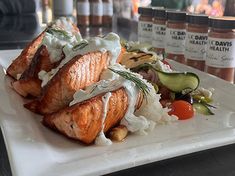 salmon and rice on a white plate with sauces in the backgroung