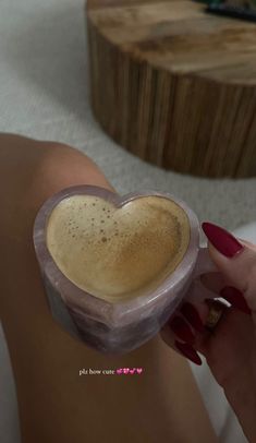 a woman's hand holding a cup of coffee in the shape of a heart