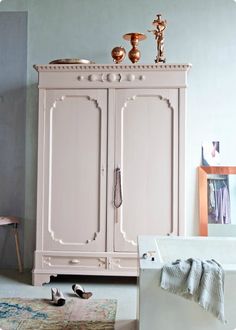 a pink armoire in a room with a rug on the floor