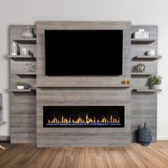 a tv mounted on the wall above a fire place in a living room with wood flooring