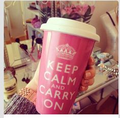 a woman holding a pink coffee cup with the words keep calm and carry on