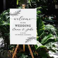 a welcome sign sitting on top of a easel in front of some potted plants