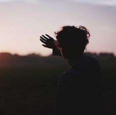 the silhouette of a person with their hands up in front of an orange and blue sky