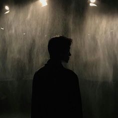 a man standing in front of a rain shower with lights shining down on his head