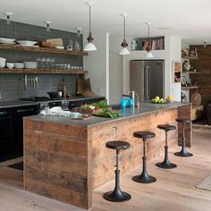 a kitchen with an island made out of wooden pallets and stools next to it