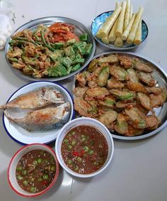 a table topped with plates and bowls filled with different types of food next to dipping sauces