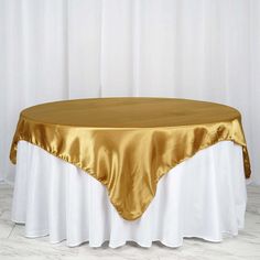 a gold and white table cloth on top of a round table