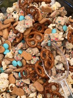 a bowl filled with cereal and pretzels next to a spoon