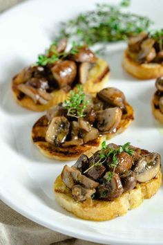 small appetizers with mushrooms and herbs on a white plate, ready to be eaten