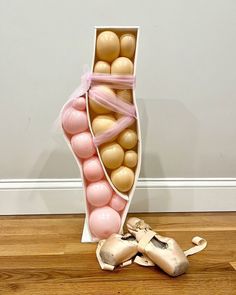 a vase filled with lots of pink and gold balloons next to a pair of shoes