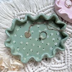 a green tray with white flowers on it and a heart shaped keychain in the middle