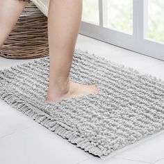 a person standing on top of a rug in front of a window next to a basket