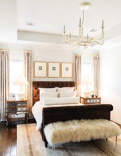 a bedroom with a bed, chandelier and two lamps on either side of the bed