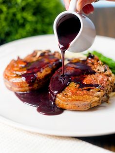 someone pouring sauce on some food on a plate