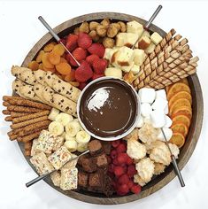 a platter filled with fruit, crackers, and chocolate sauce on top of it