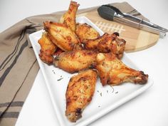 some chicken wings on a white plate next to a knife and fork