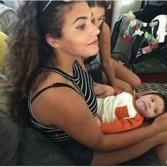 a woman holding a baby in her arms and looking at the camera while sitting on a couch