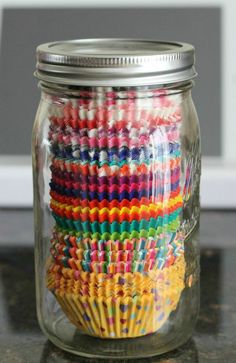 a glass jar filled with lots of colorful crayon pencils on top of a table