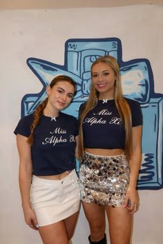 two young women standing next to each other in front of a blue and white wall