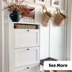 there is a white cabinet with baskets on it and pictures above the cupboards in the room