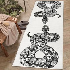 a white runner rug with black and white snakes on the floor next to a chair