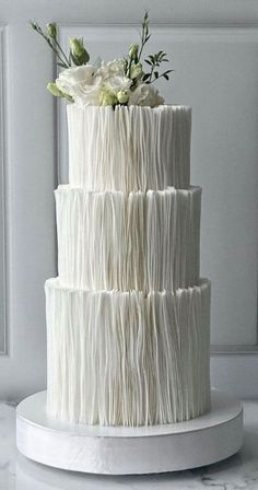 a three tiered white cake with flowers on top