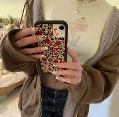 a woman holding up her phone case with flowers on it