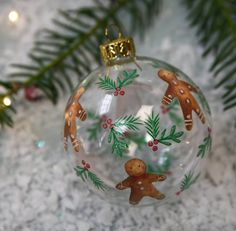 a glass ornament decorated with gingerbreads and holly