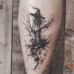 a person with a hat and tree branches tattoo on their leg, while wearing a witch costume