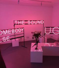 the room is filled with pink lighting and various items on display, including signs that spell out the word'the sound somebody else '