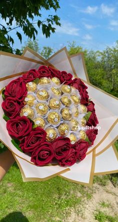 a bouquet of red roses and chocolates in the shape of a heart is held by someone's hand