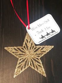 a gold star ornament hanging from a red string on a wooden table with a tag