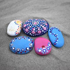 five painted rocks sitting on top of a sandy beach