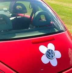 a red car with a flower sticker on it's windshield and the back window