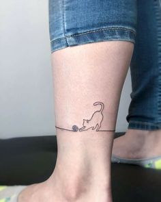 a woman's foot with a cat tattoo on her left ankle and a ball of yarn in the foreground