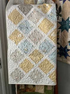 two quilts are hanging on the wall next to each other, one is yellow and white